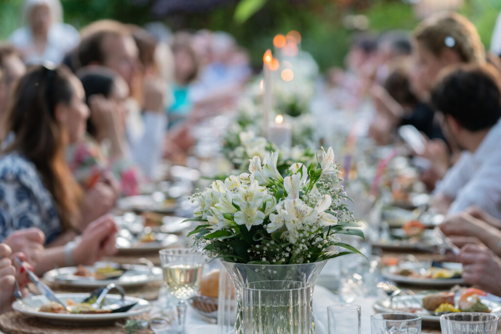 Et dækket bord med gæster ved- de er uskarpe, mens blomsten på bordet er skarpt belyst