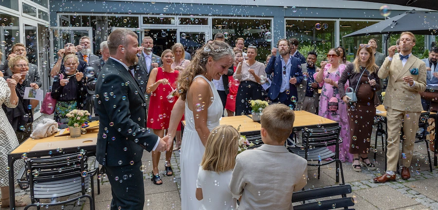 Festfotograferne har her fotograferet brudeparret, der går gennem en festlig flok af bryllupsgæster omgivet af sæbebobler.