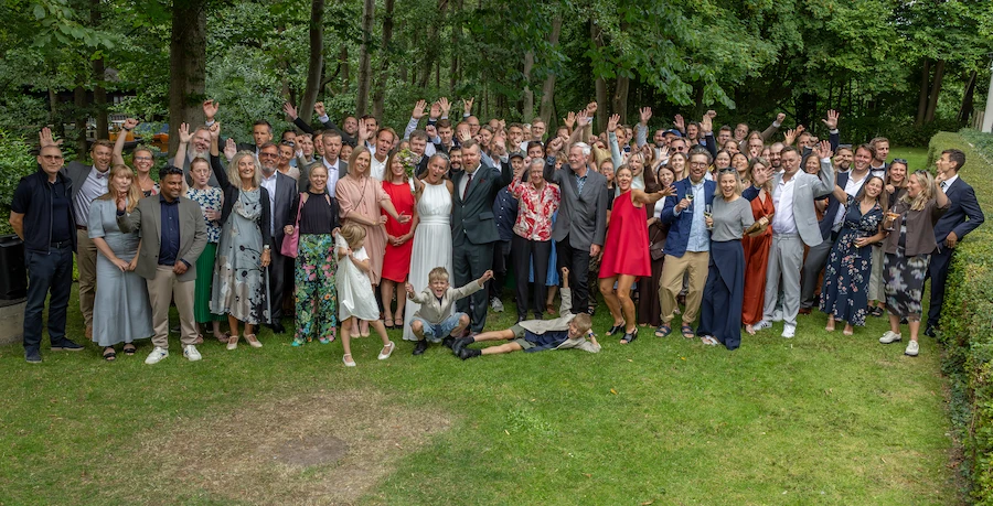 Festfotograferne har her fotograferet en stor gruppe bryllupsgæster, der er samlet på græsplænen og fejrer brylluppet.
