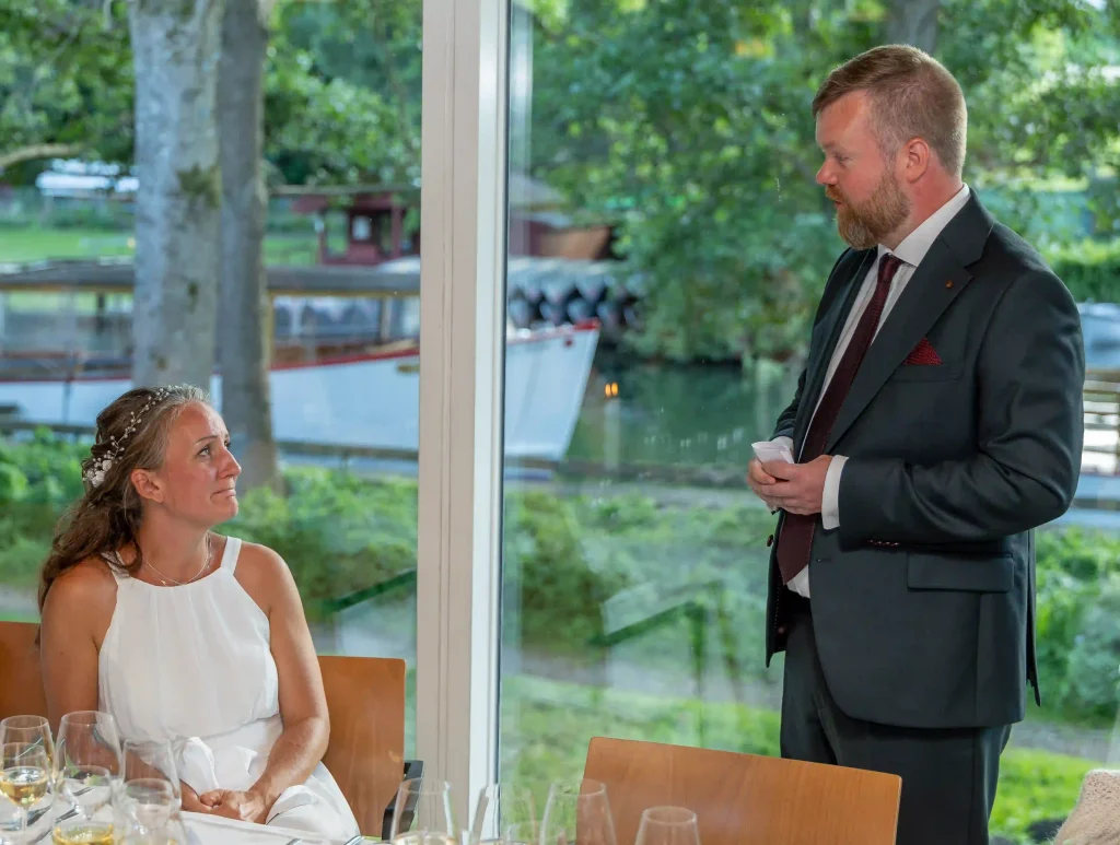 Festfotograferne har her fotograferet en bryllupstale, hvor brudgommen står og taler til bruden under middagen.
