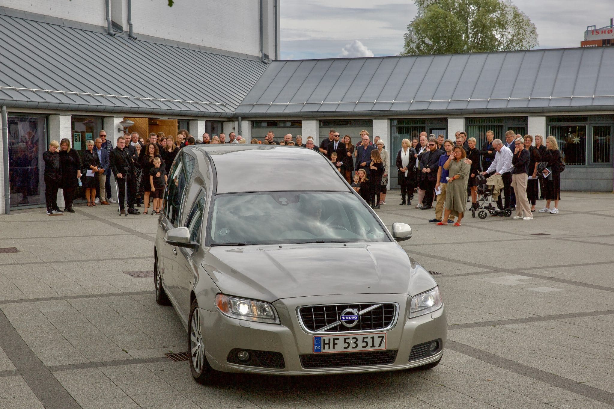 Bedemandsbil kører væk. Familien står i baggrunden