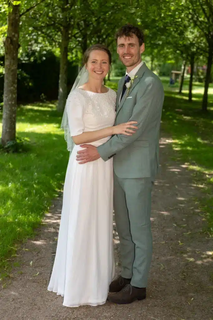 Festfotograferne har her fotograferet brudeparret, som står sammen på en sti i grønne omgivelser på deres bryllupsdag.