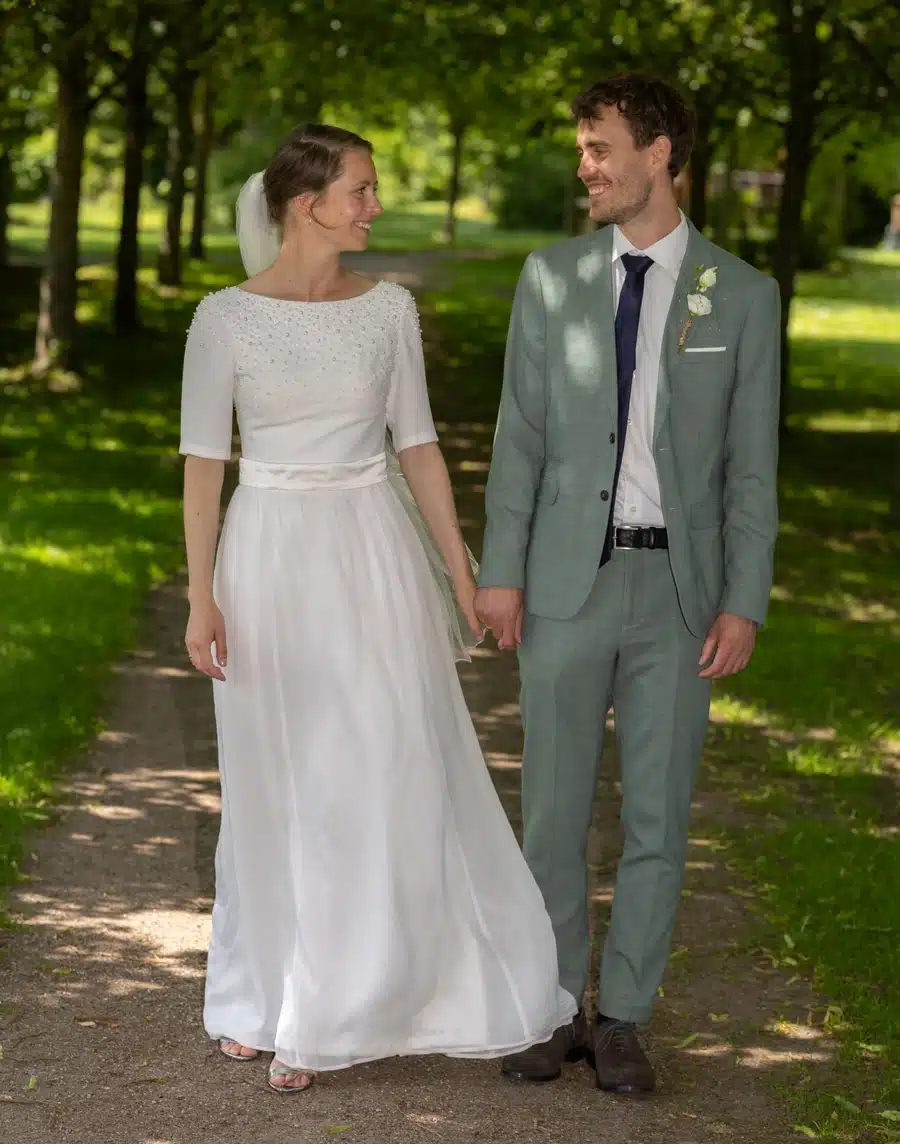 Bryllup 16 Festfotograferne har her fotograferet et brudepar, der går hånd i hånd på en sti i grønne omgivelser på deres bryllupsdag