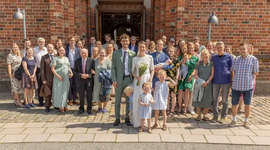 Bryllup 15 Festfotograferne har her fotograferet ved et bryllup. Brudepar med familie og venner samlet til gruppefoto foran en kirke.