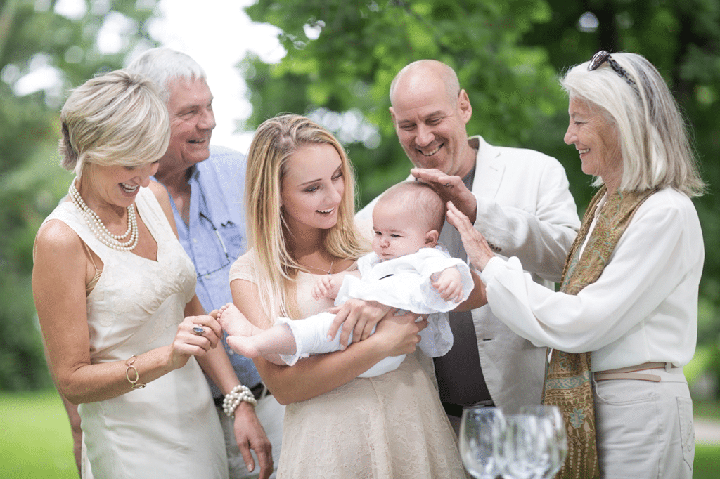 Fotografen har her fotograferet Ved en barnedåb. på billedet ses en familie stående omkring moderen, der holder barnet