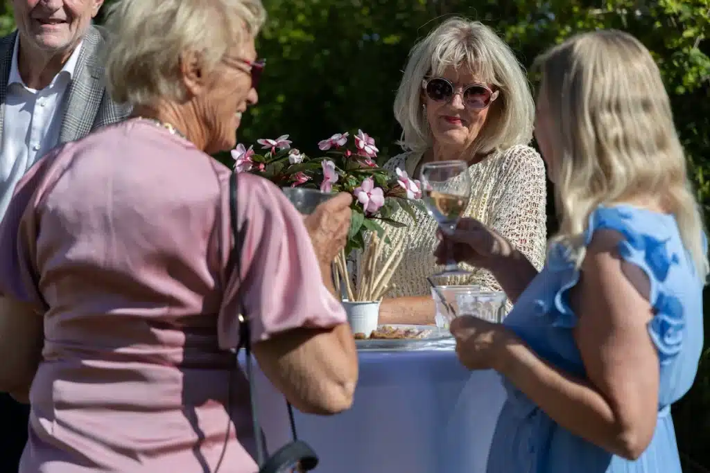 Festfotograferne har her fotograferet til en fødseldagshavefest. På billedet ses 3 kvinder stående ved et rundt højbord. De snakker og drikker vin