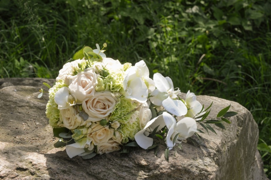 Festfotograferne har her fotograferet en brudebuket med blomster i hvide nuancer liggende på en sten