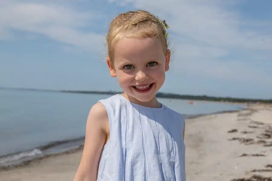 Festfotograferne har her fotograferet en smilende lille pige på stranden under bryllupsdagen.