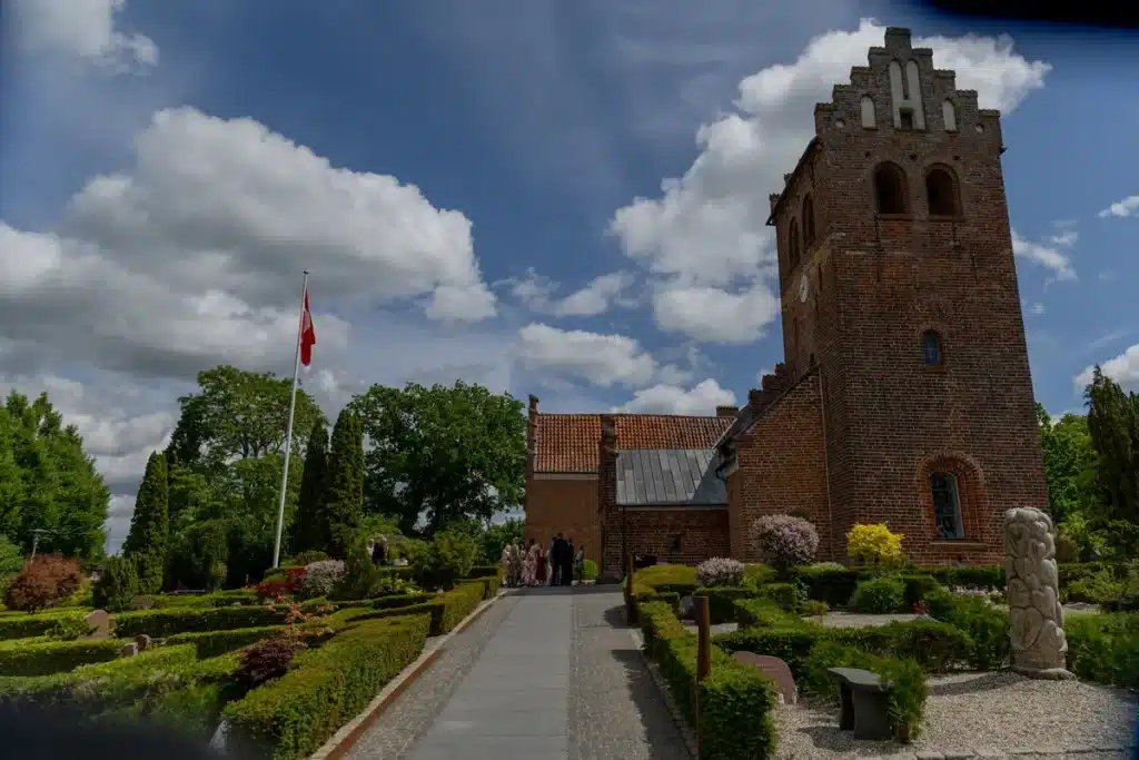 Bryllup 17 Stenløse Kirke med kirkegården i forgrunden. Blå himmel og få skyer på himlen